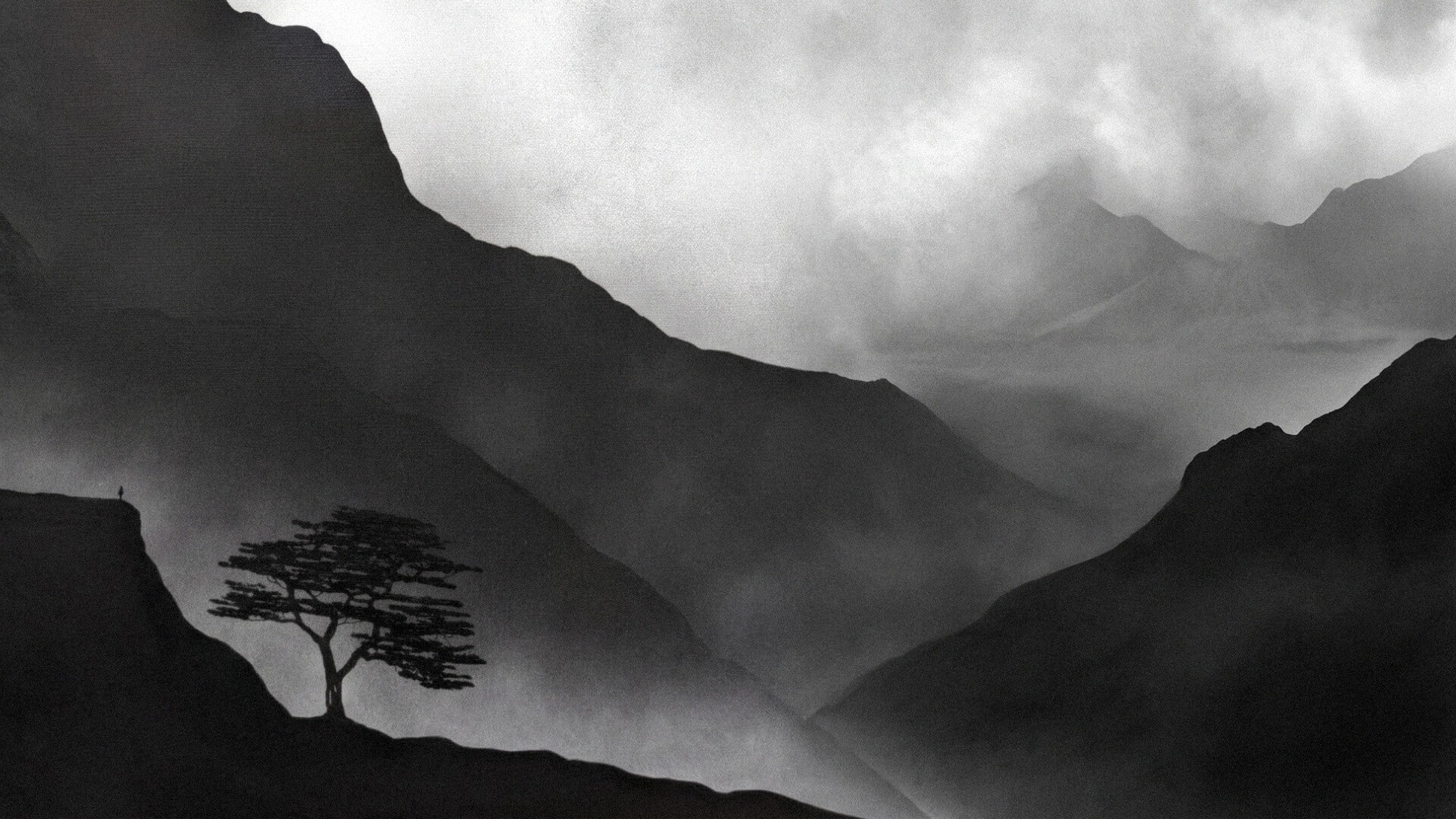 A dramatic, high-contrast monochrome photograph of layered, misty mountain ranges. A solitary, silhouetted tree stands on a dark ridge in the foreground, perfectly capturing the moody aesthetic of the landscape painting workshop.